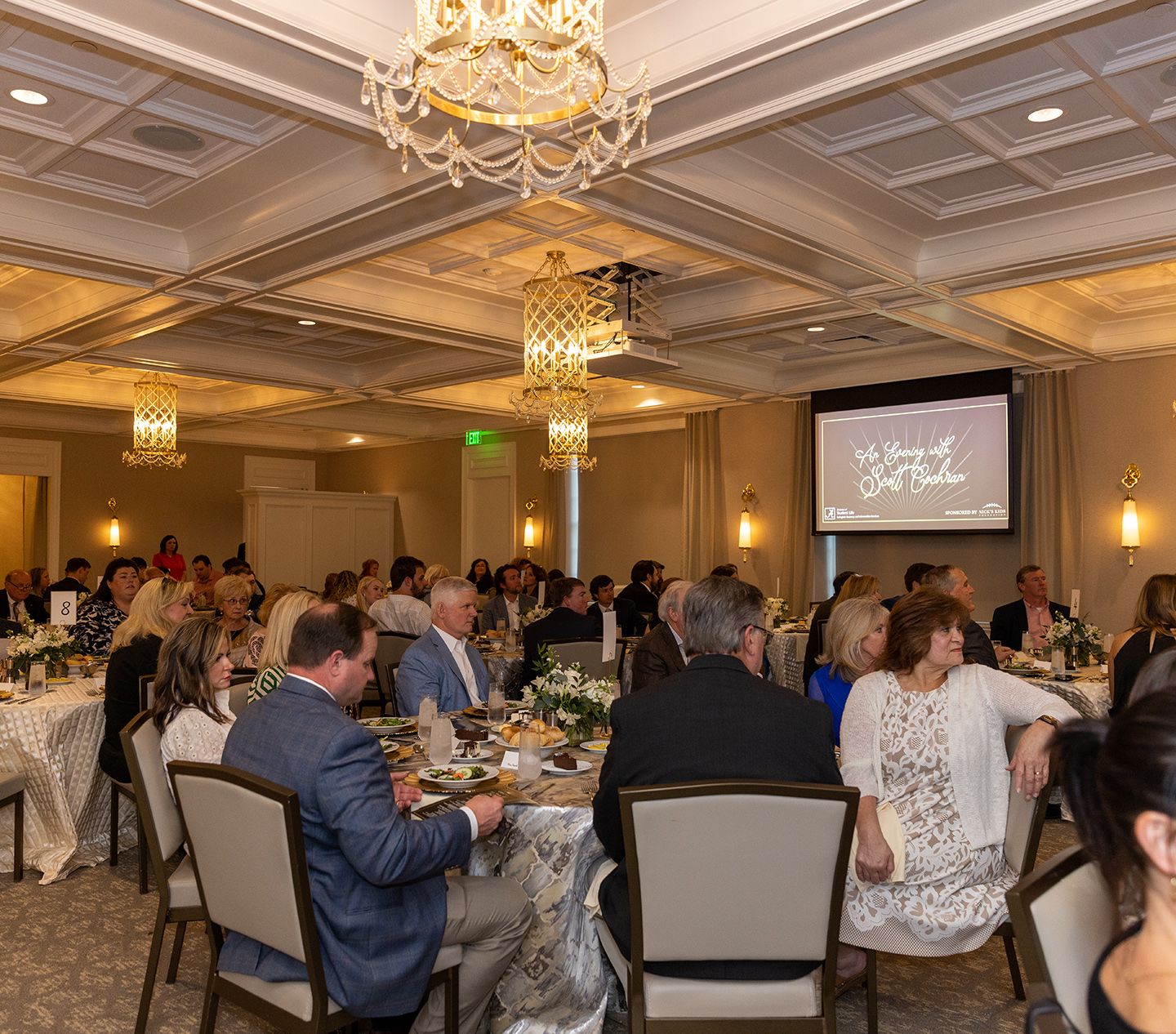 large room of tables with people sitting at a banquet