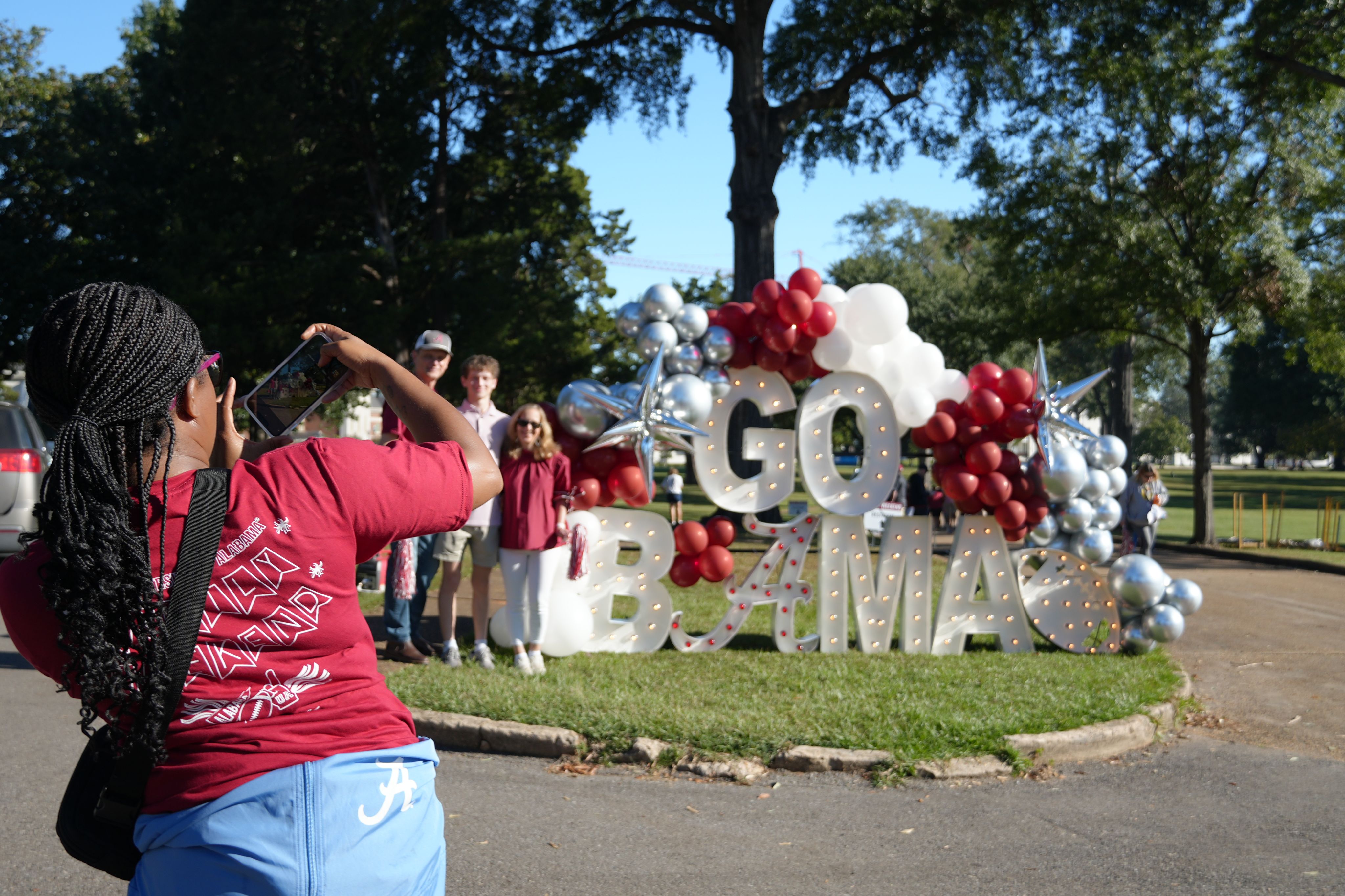parents pose with a Go Bama sign