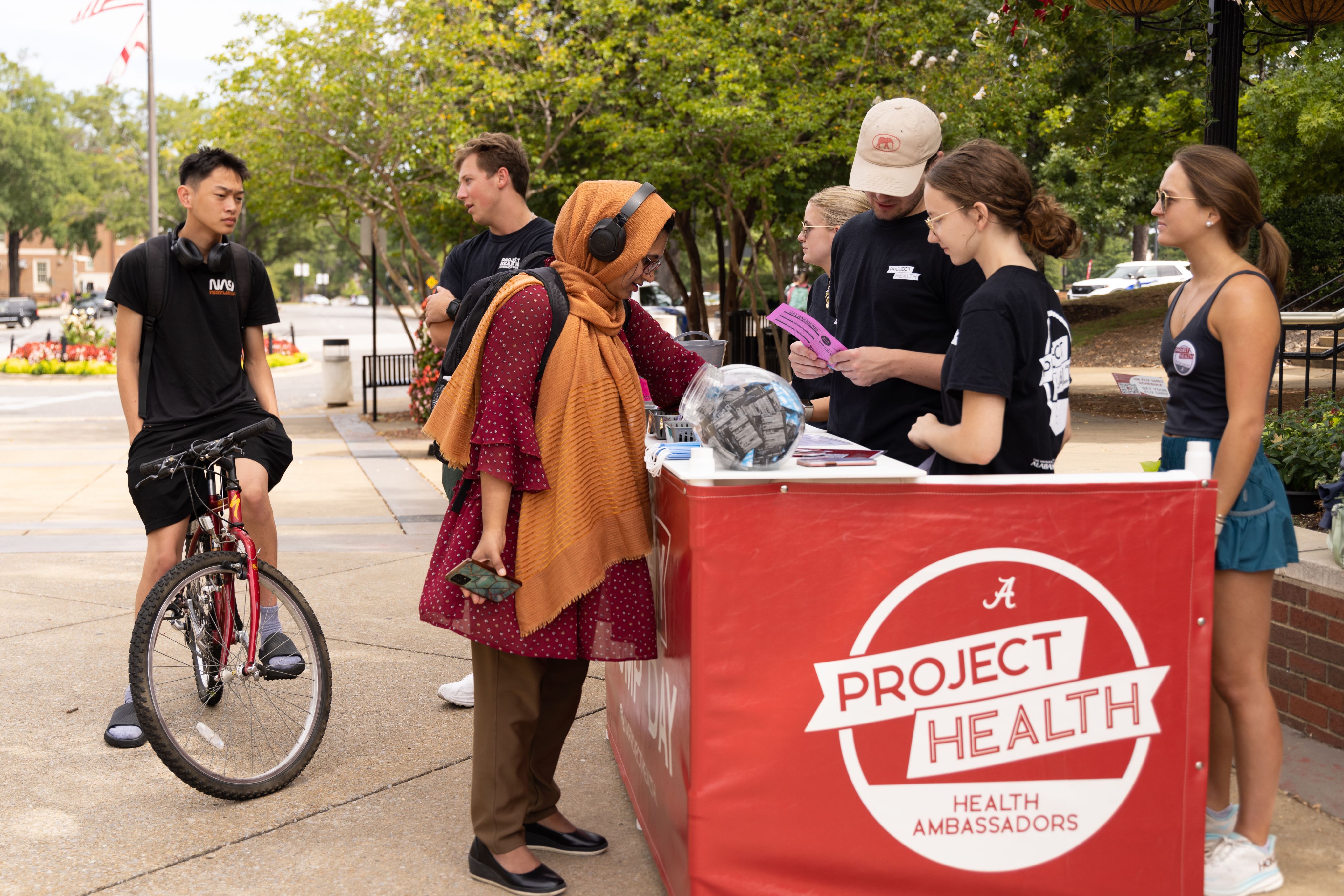 two students talk with a volunteer at the health hut