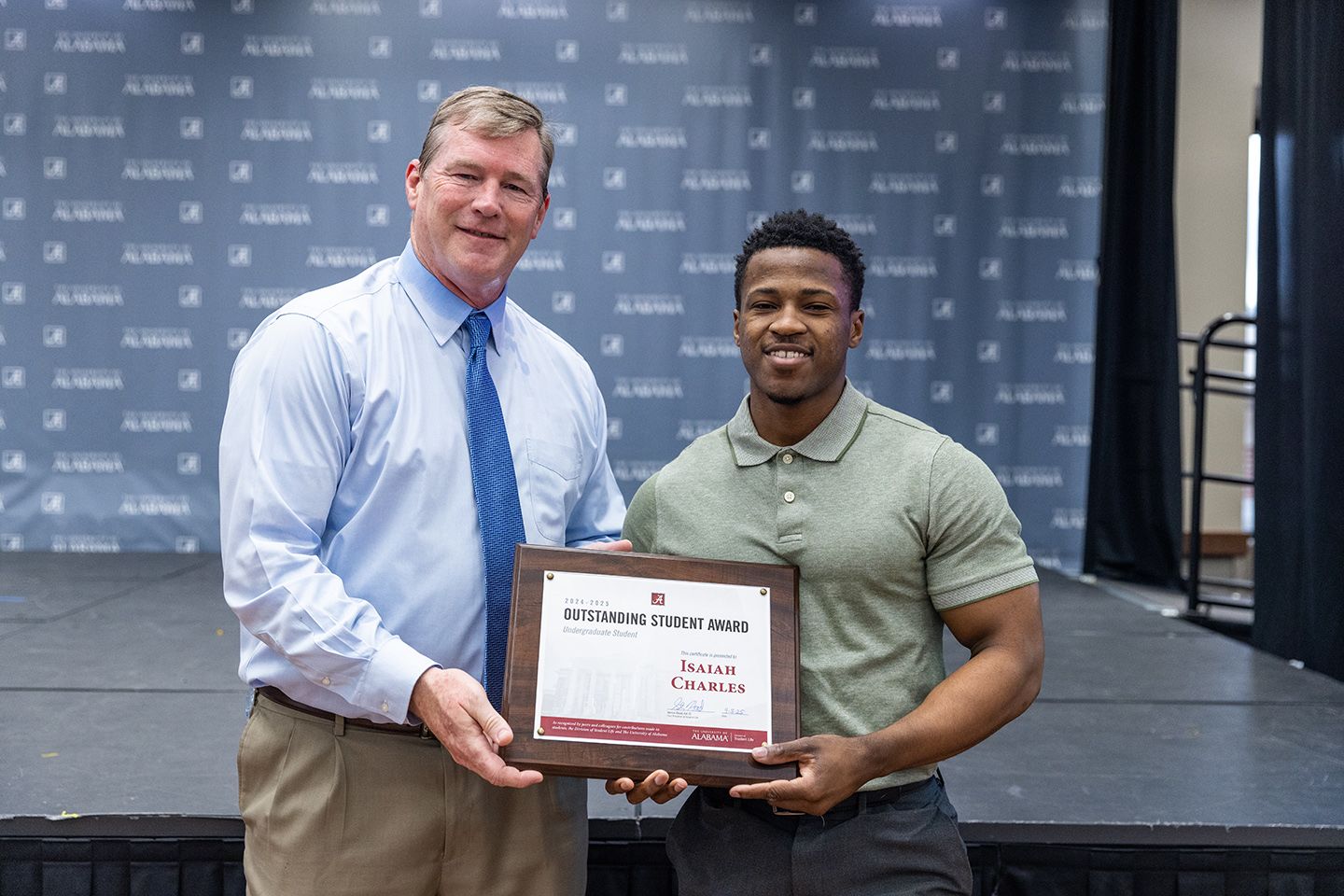 Isaiah holds the award and poses for a picture with Dr hood