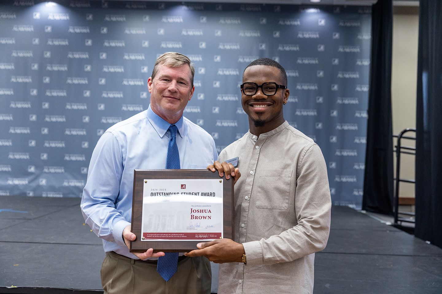 Joshua Brown holds the award and poses for a picture with dr hood