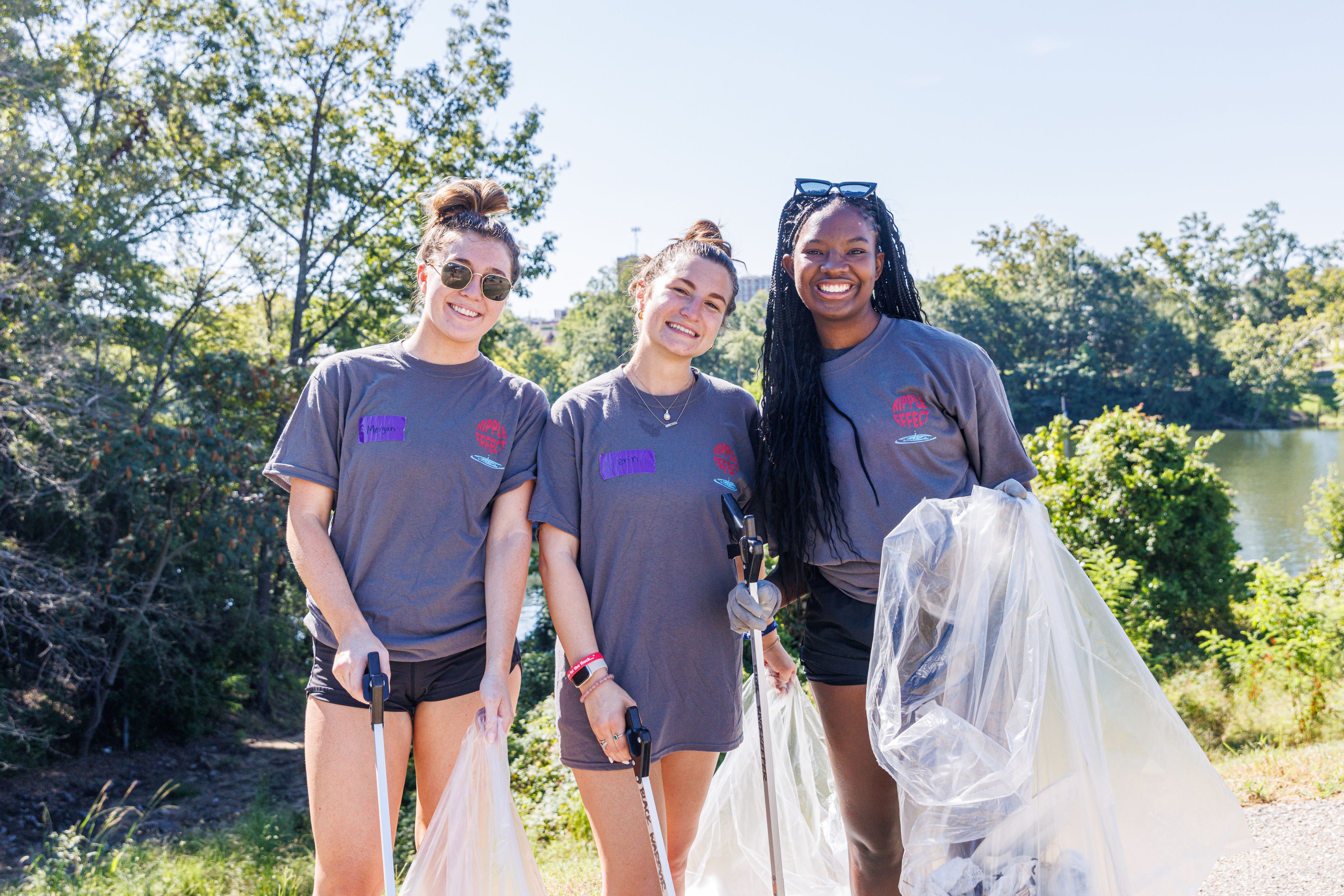3 students pick up trash and smile