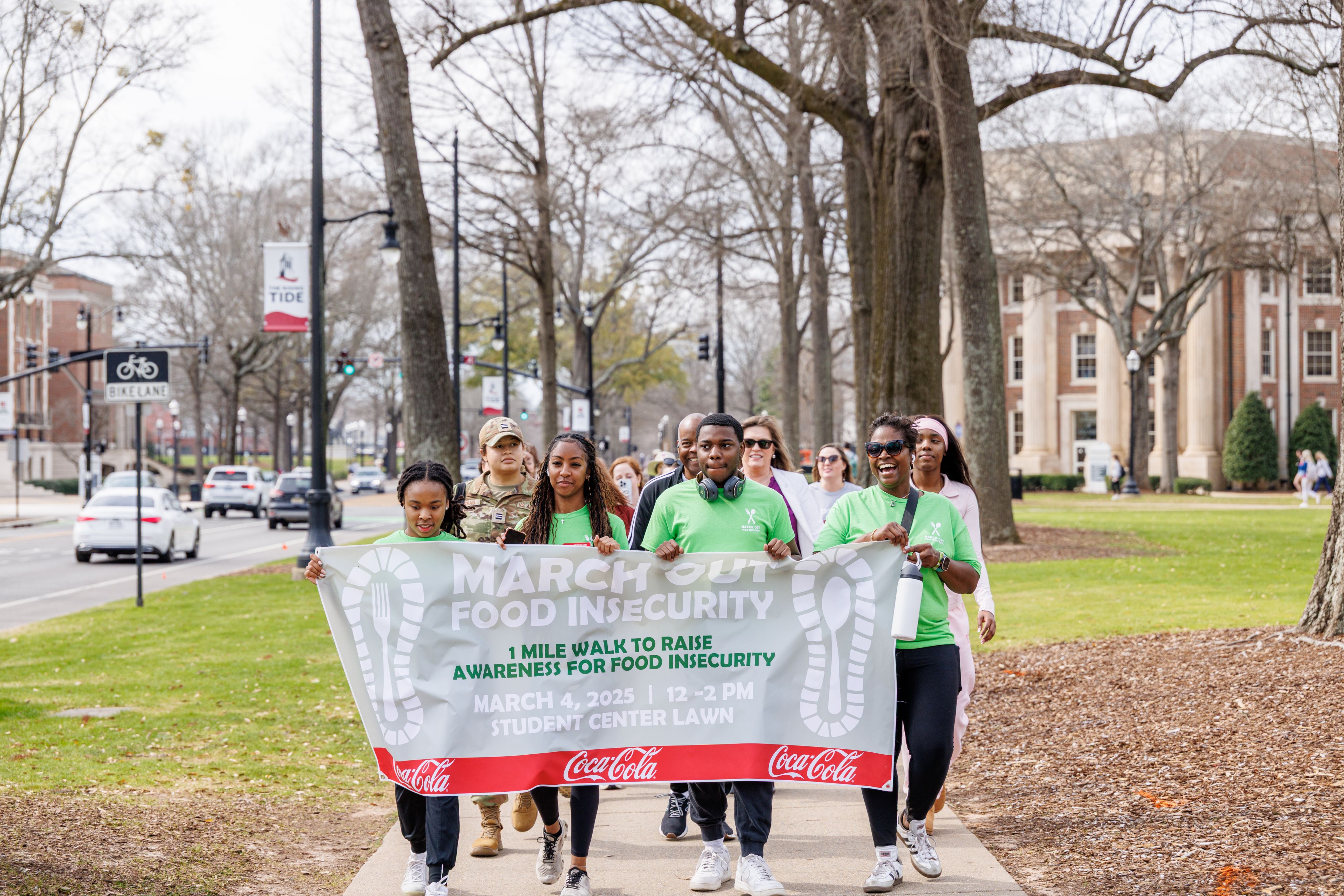 Students hold banner and walk on the Quad