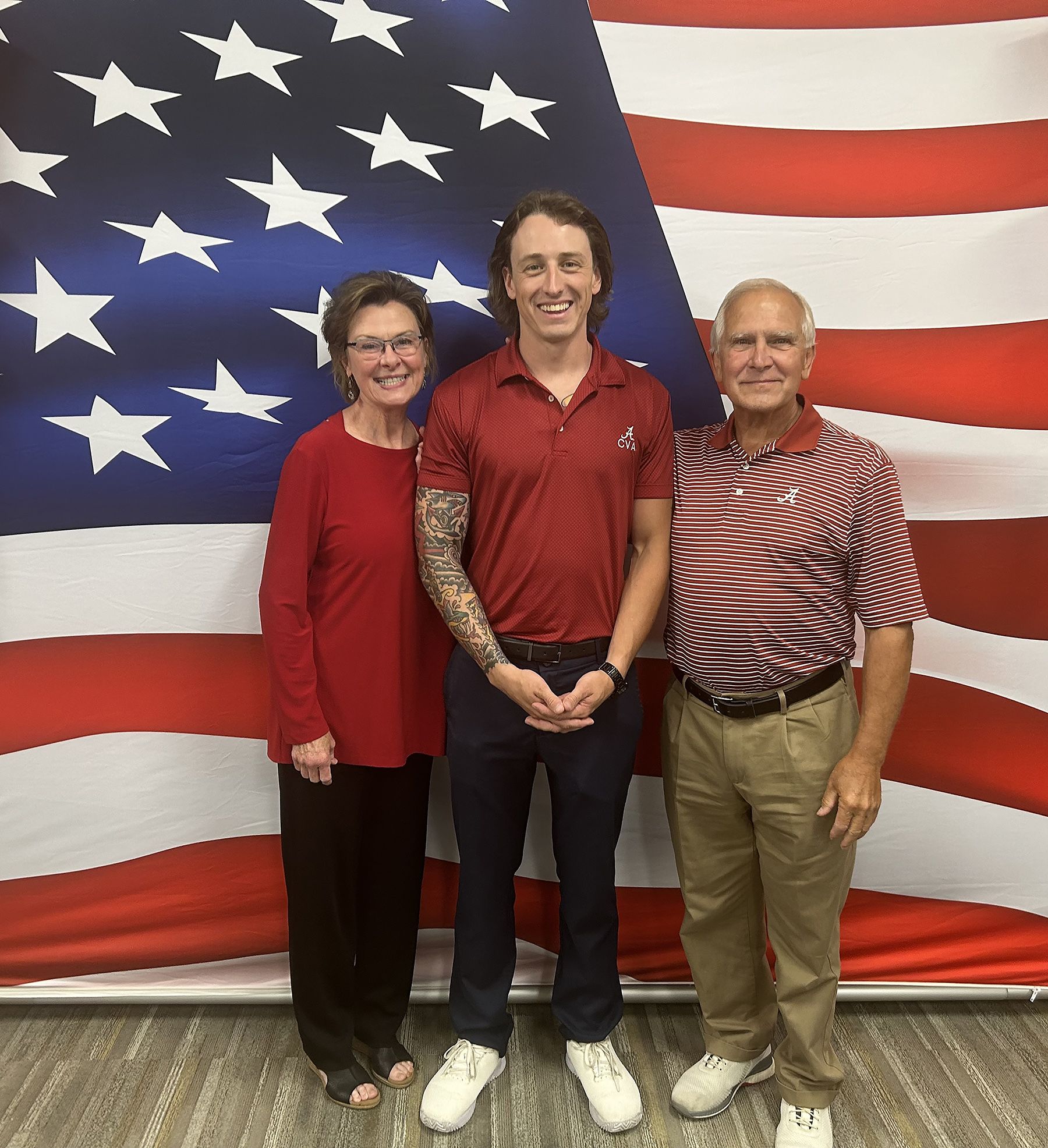 Rudisill couple poses with student in front of American flag
