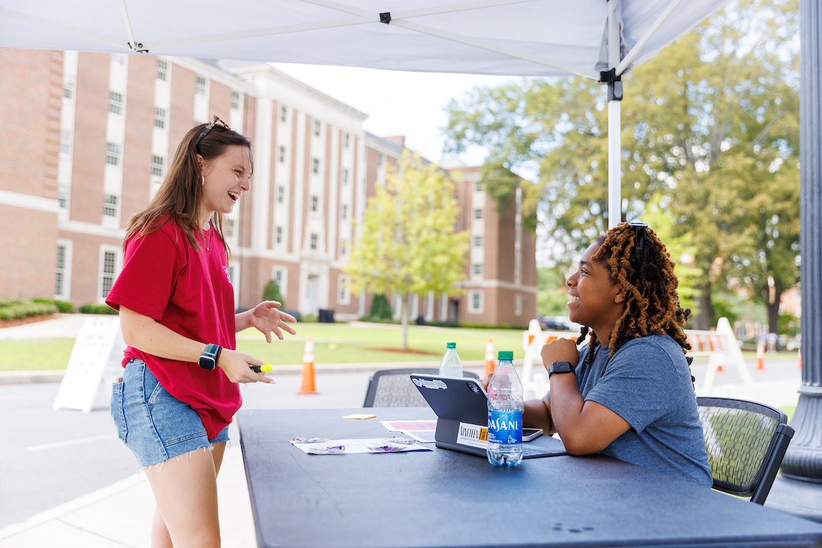 student registering at a check in table with both smiling