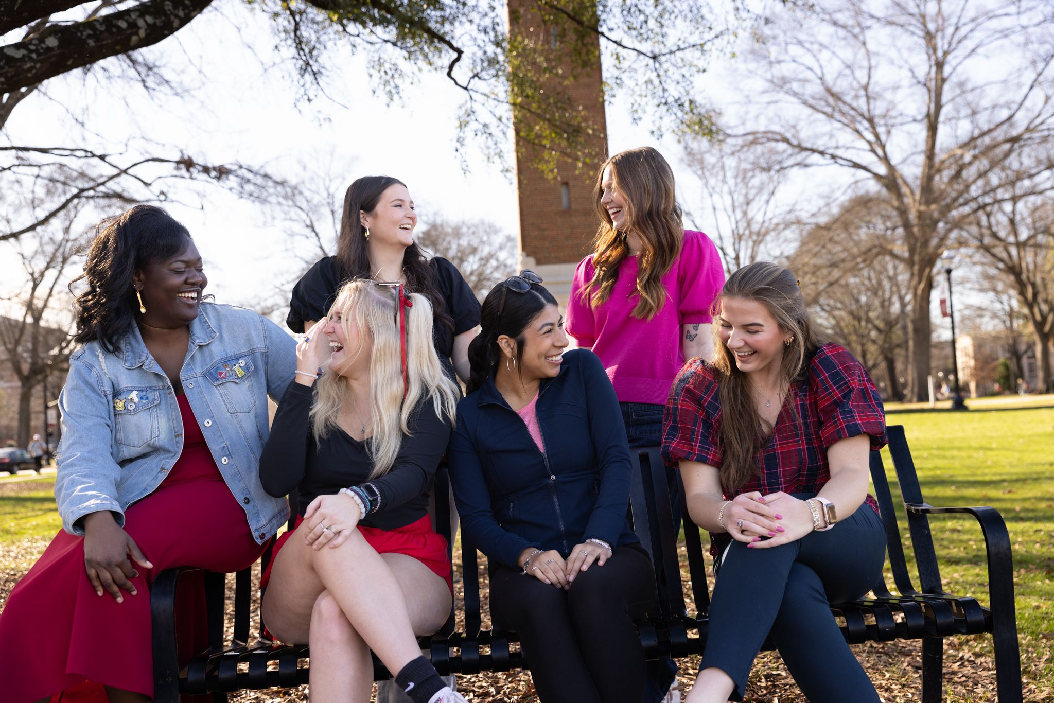 group of students sit on bench and laugh