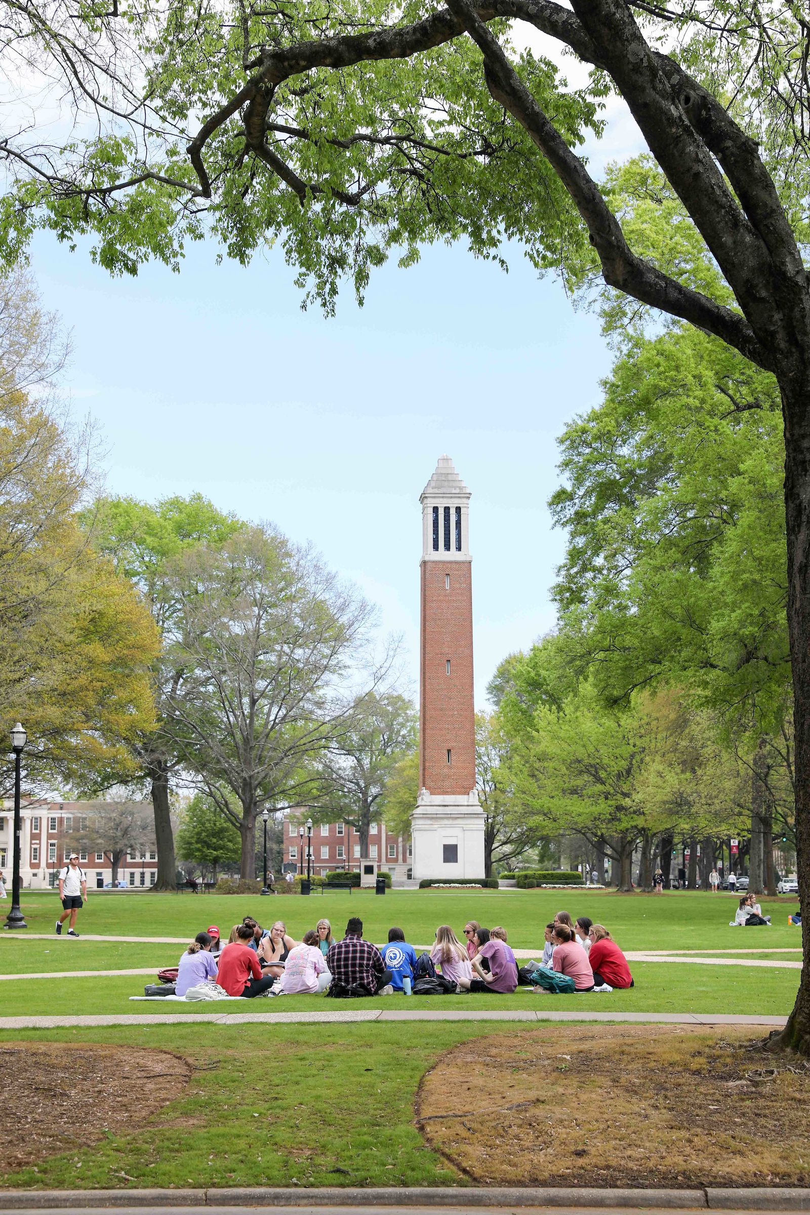 students sit in a circle on the quad with denny chimes in the background