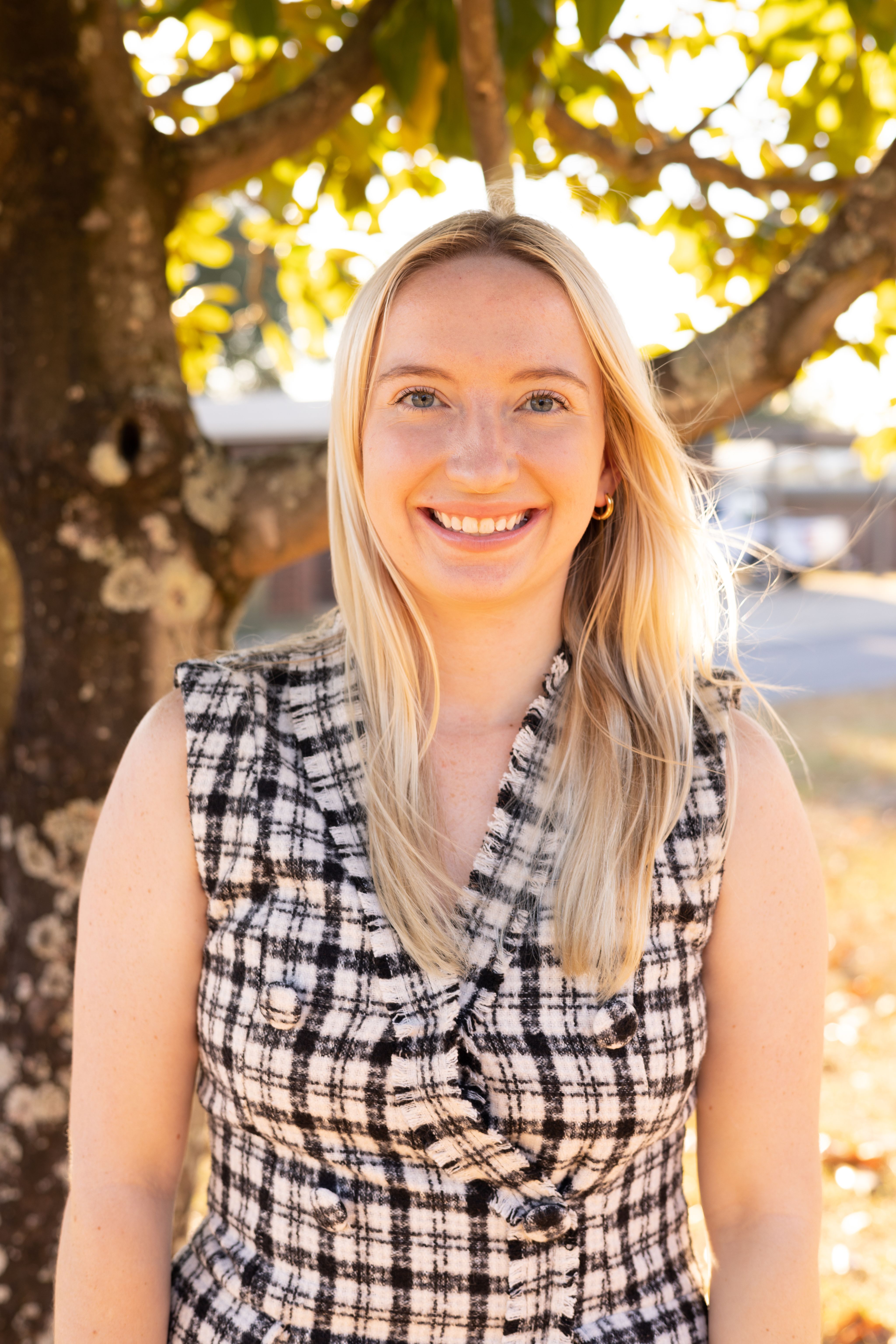 emma grace smiles into the camera with a tree behind her