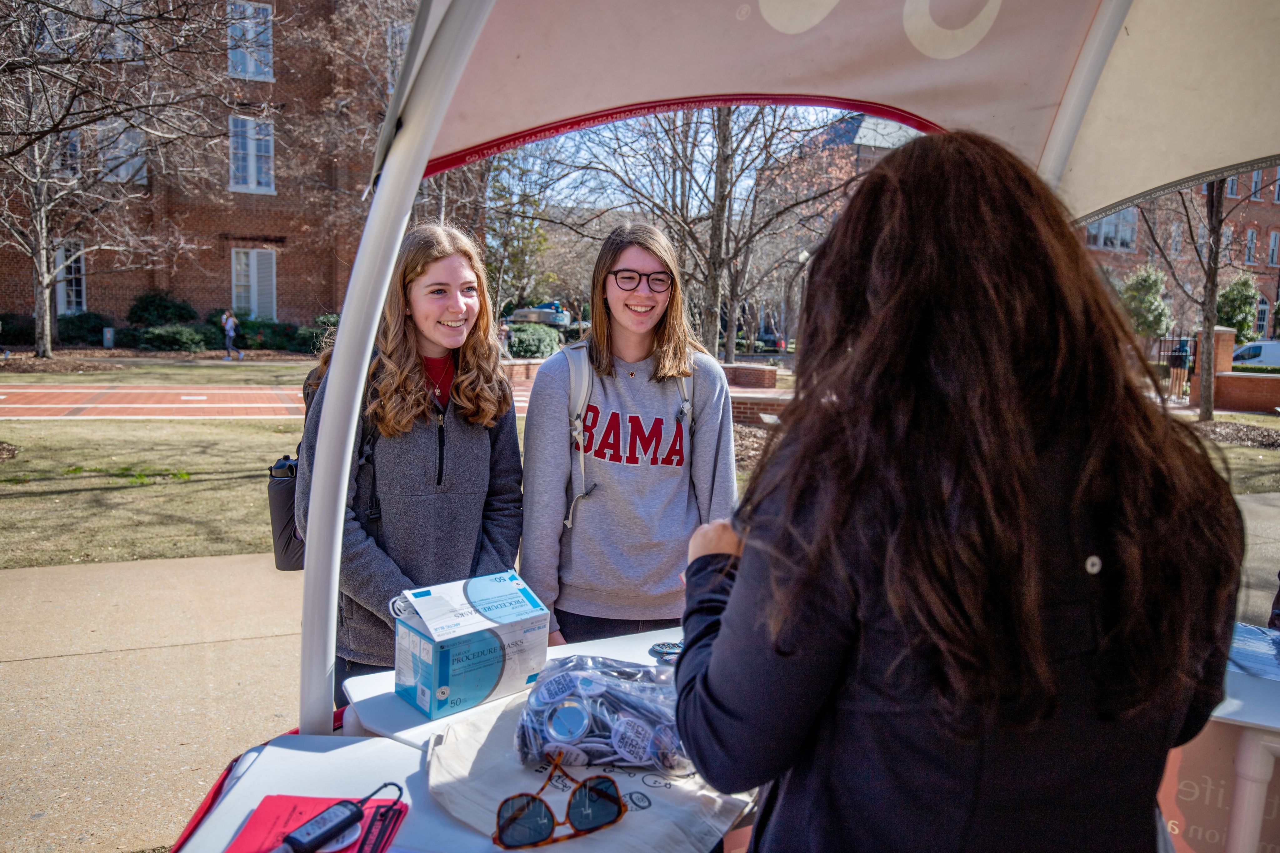 two students talk with a volunteer at the health hut