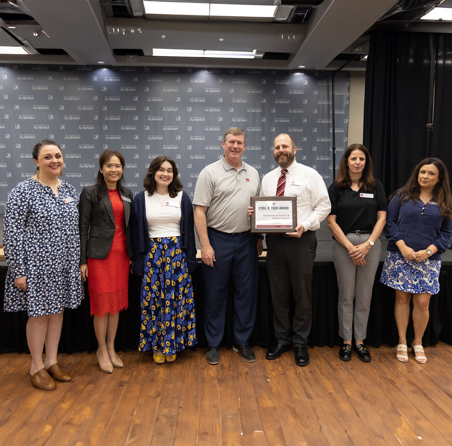 the international student scholar services team holds the award and poses for a picture with dr hood