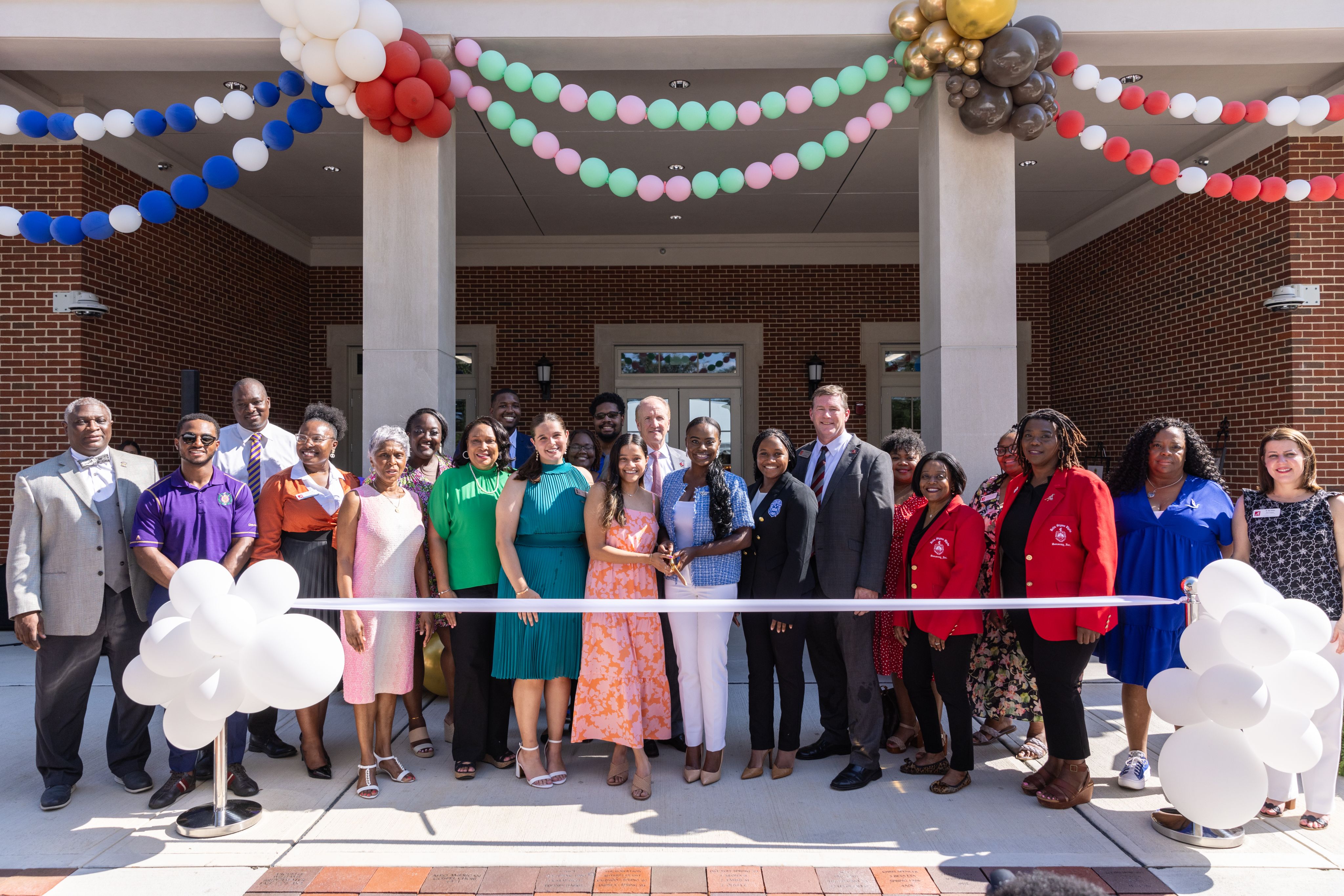 a large group of people pose for a photo at the greek assembly hall ribbon cutting ceremony
