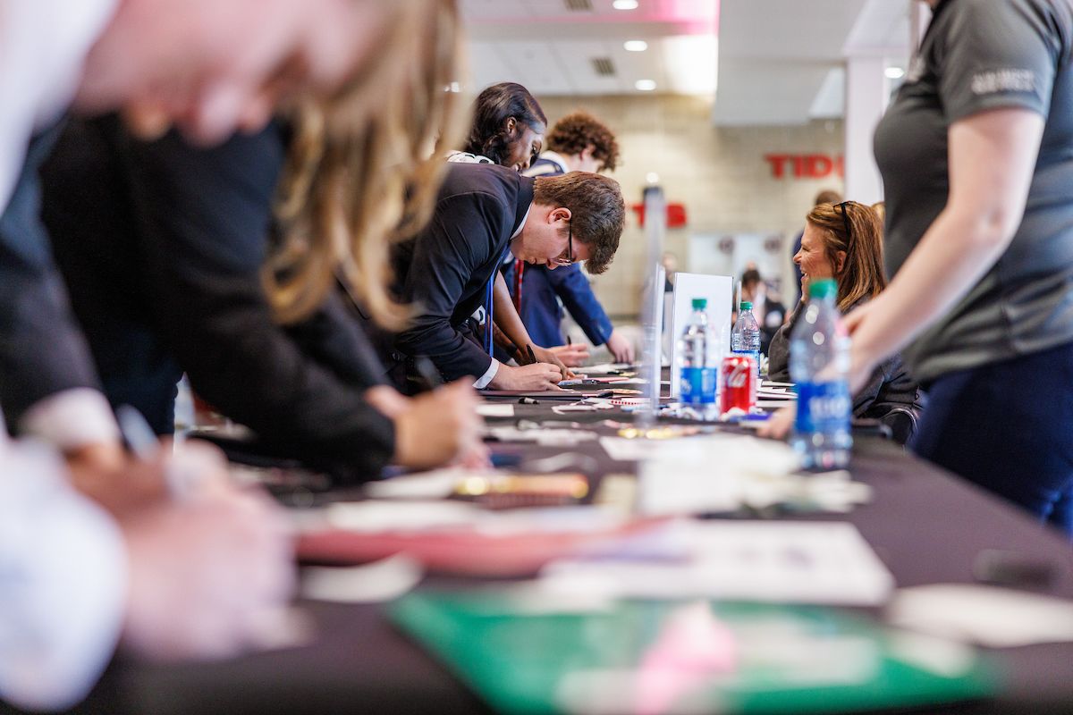 students lean over a table and fill out information for a career fair