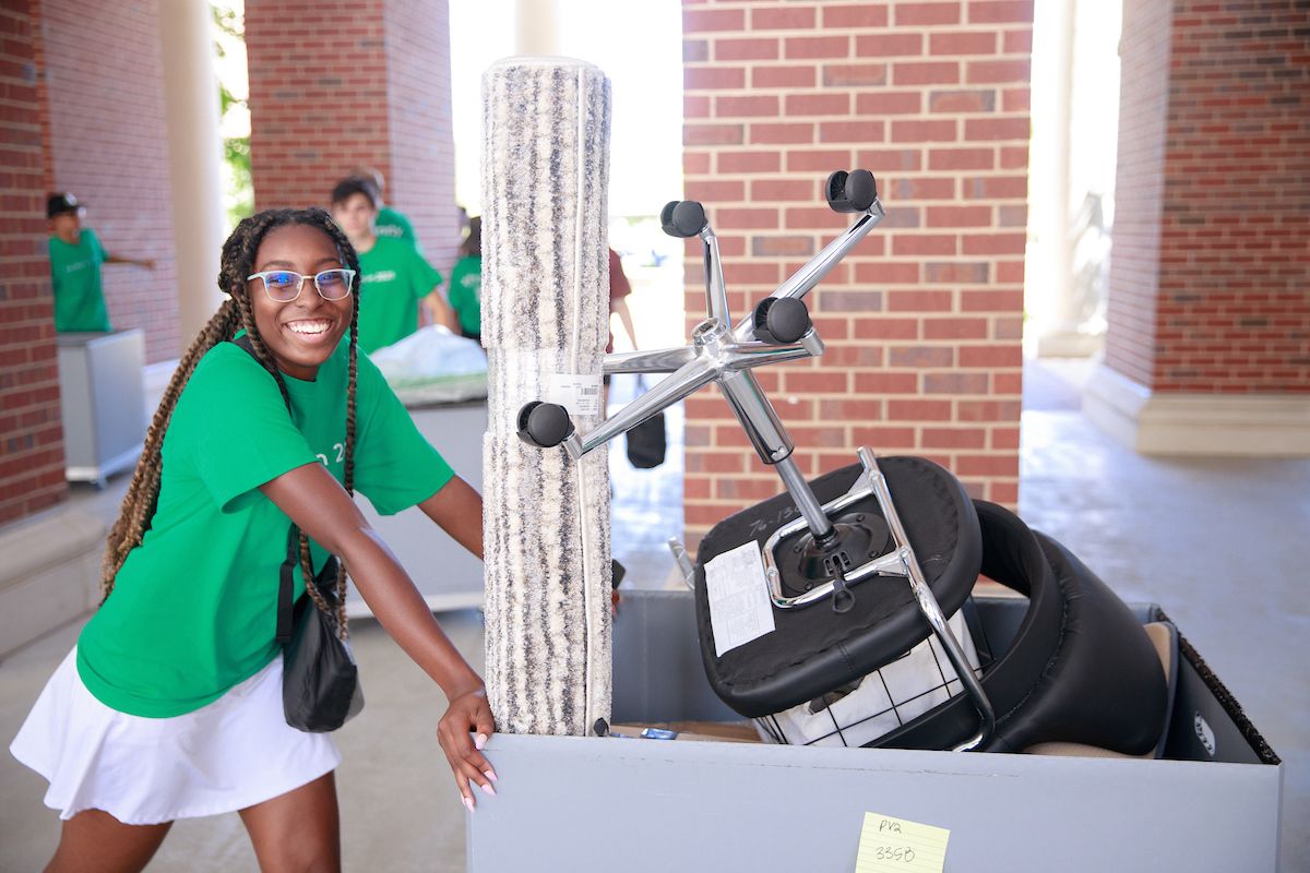 a student pushes a cart full of dorm room supplies for housing move-in day