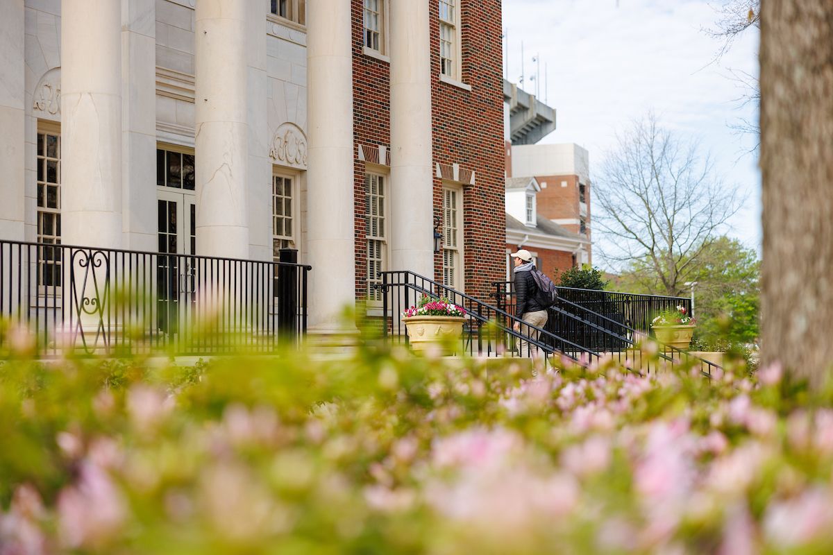 a student walks up stairs and in between large columns
