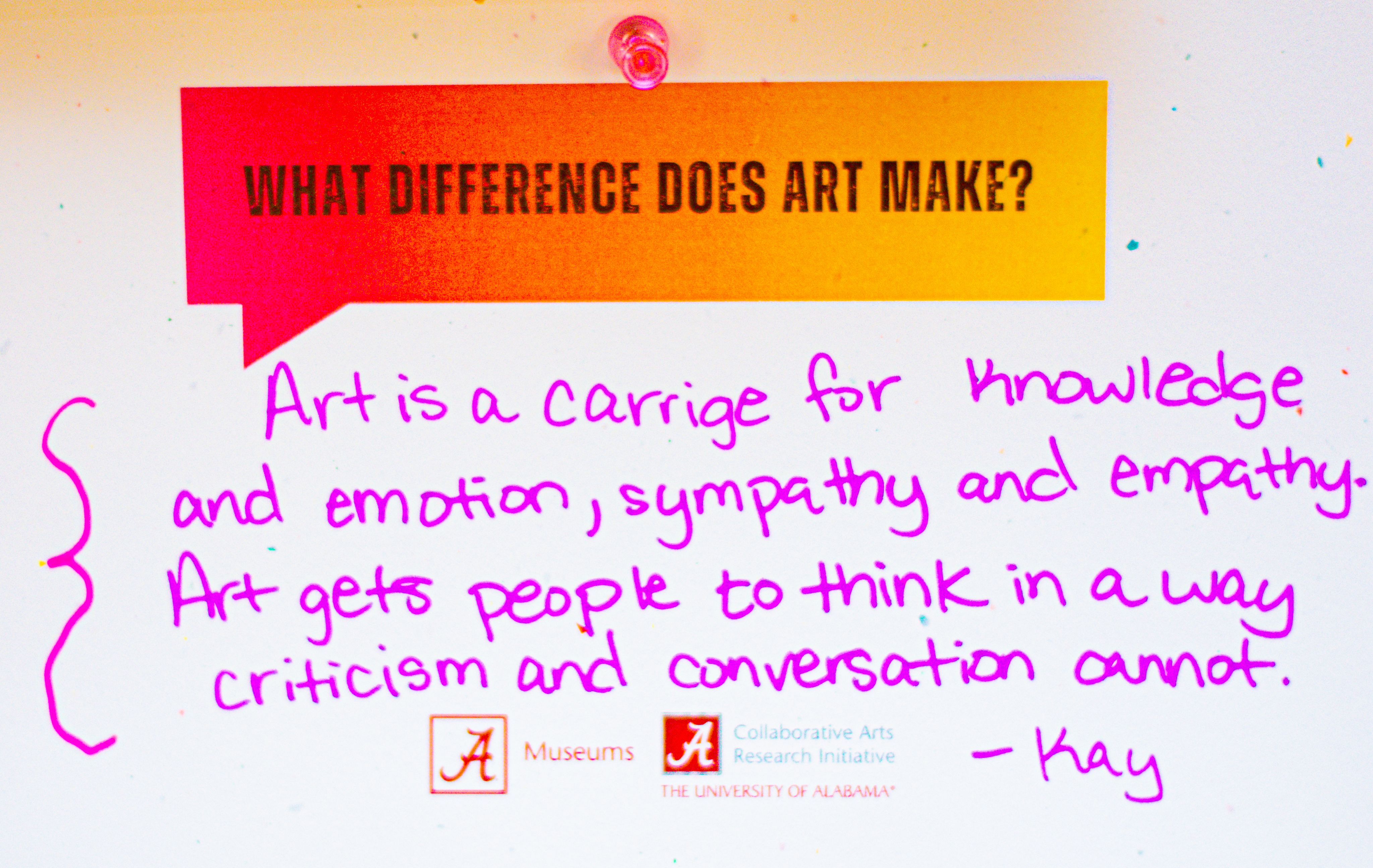 A colorful note on a board with "What difference does art make?" printed on top, followed by a handwritten message discussing the impact of art. It mentions "Art is a carriage for knowledge and emotion" and includes logos for The University of Alabama Museums and the Collaborative Arts Research Initiative at The University of Alabama. Signed by Kay.
