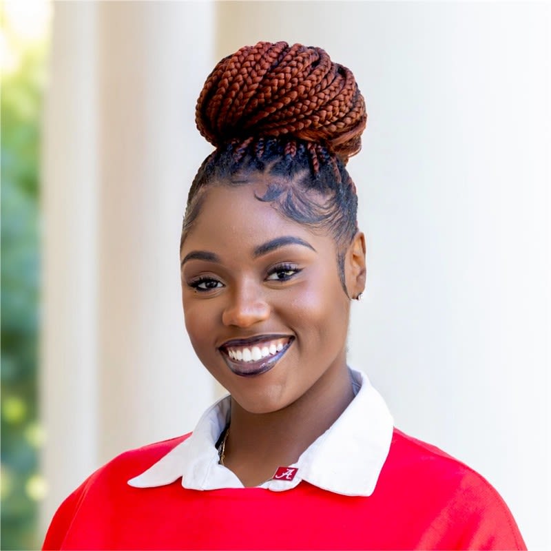Close-up portrait of a smiling individual with braided updo hairstyle.