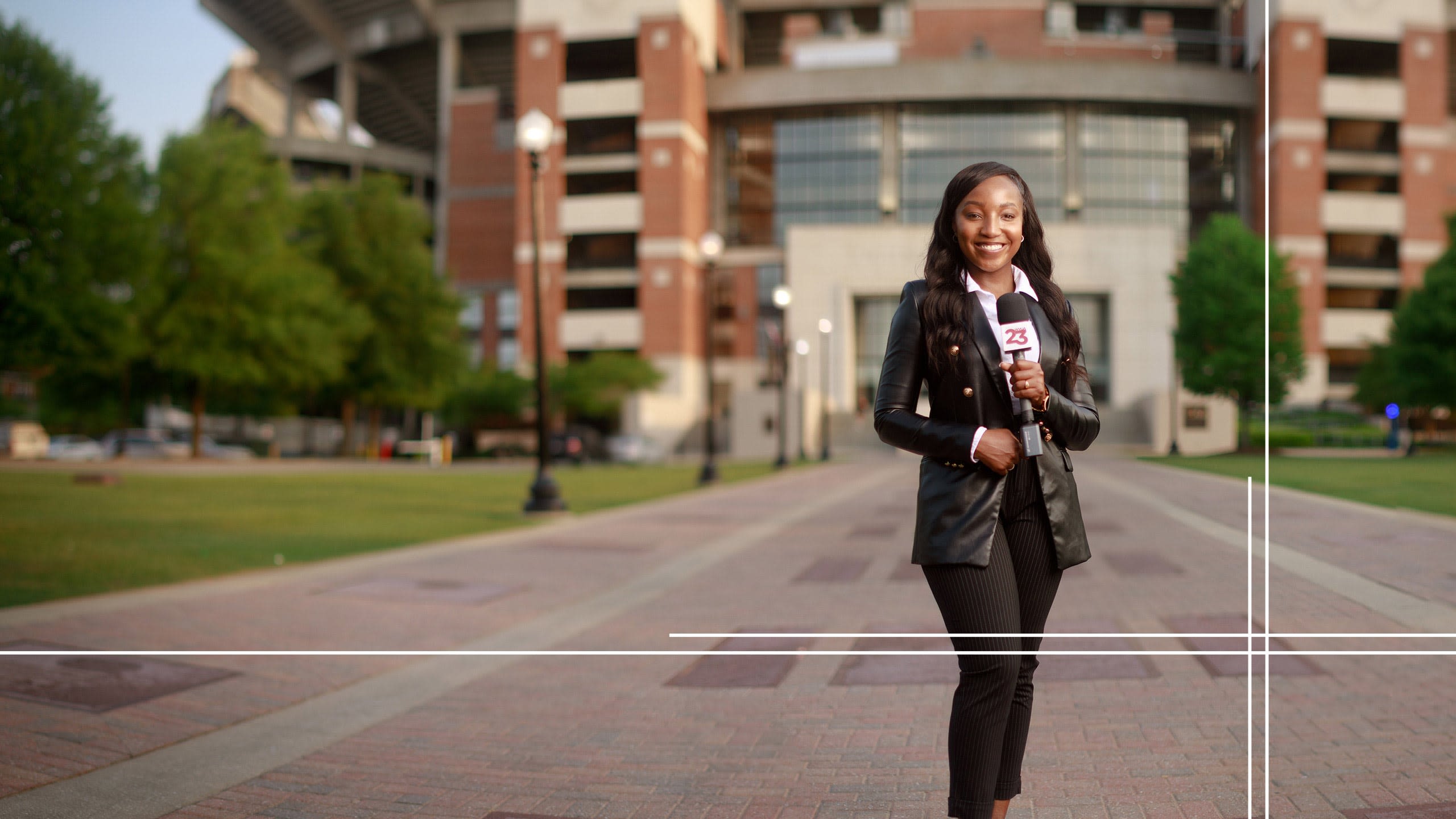 Kennedy stands on the Walk of Champions holding a microphone preparing to go live on camera.