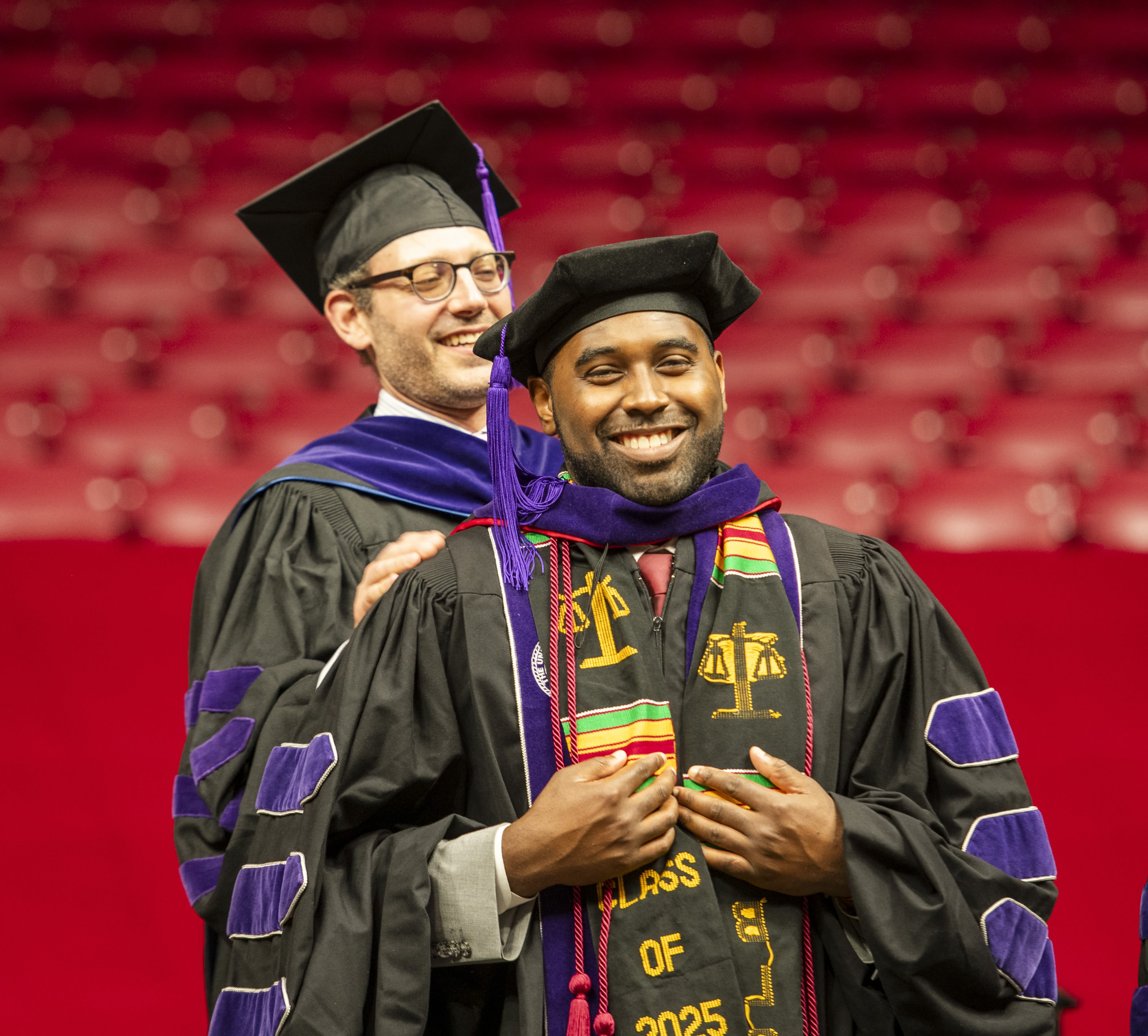 A law professor, Russell Gold, places a hood on a law school graduate, Malcolm Lowe, during the commencement ceremony.