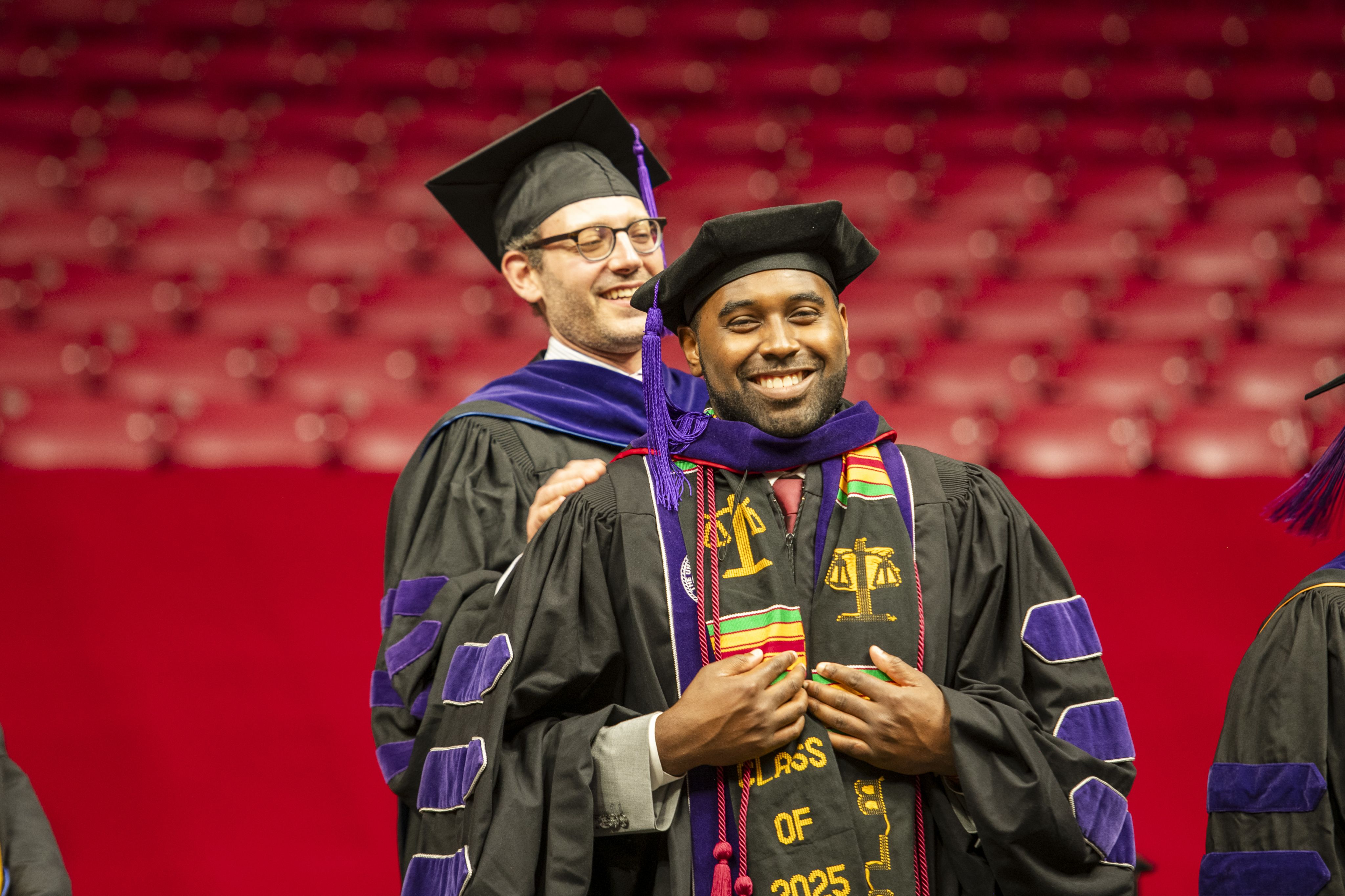 A law professor, Russell Gold, places a hood on a law school graduate, Malcolm Lowe, during the commencement ceremony.