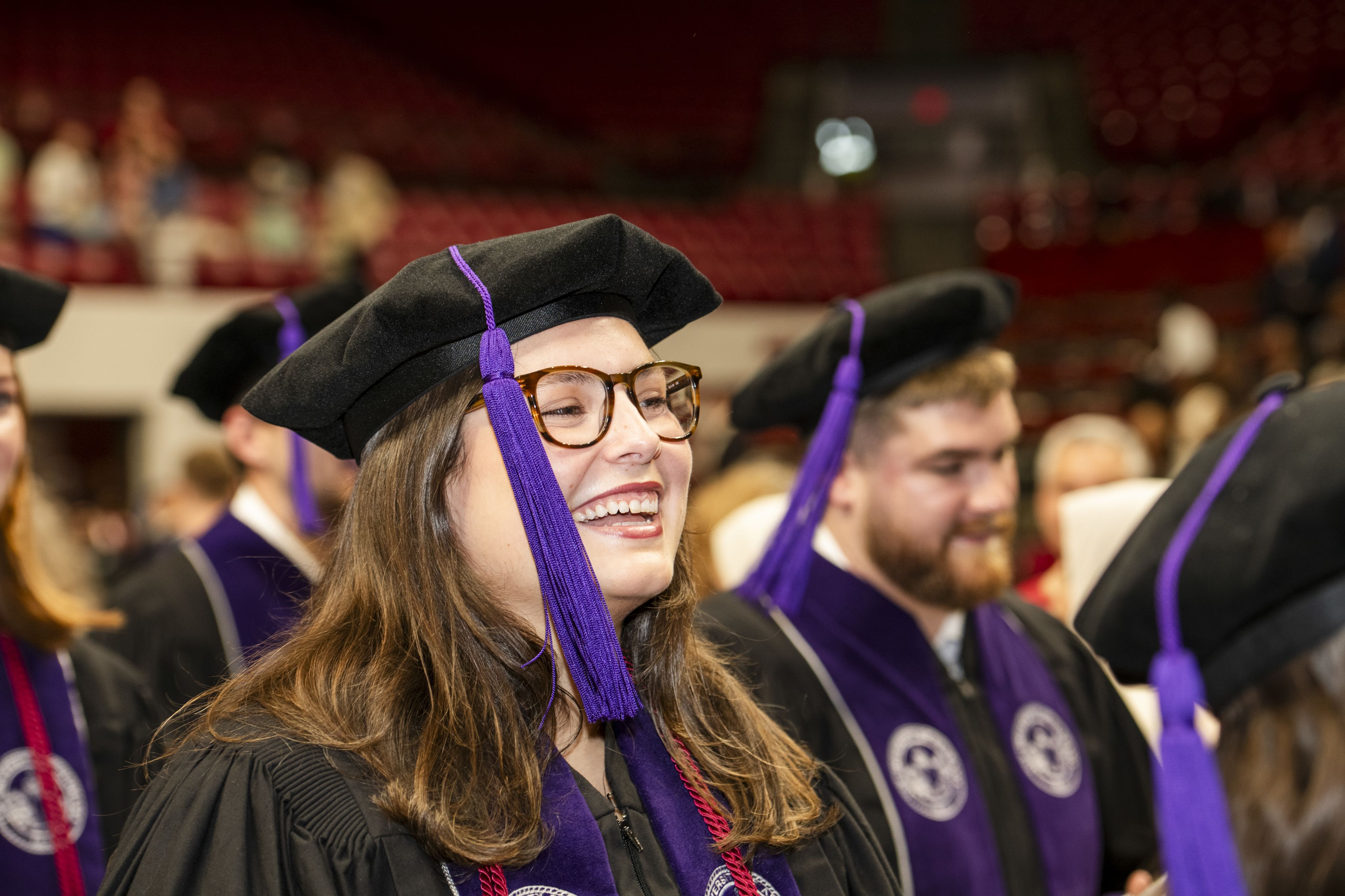 A woman wearing a graduate cap smiles