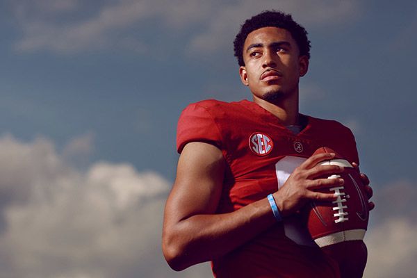 Bryce Young holds a football and gazes into the distance. 