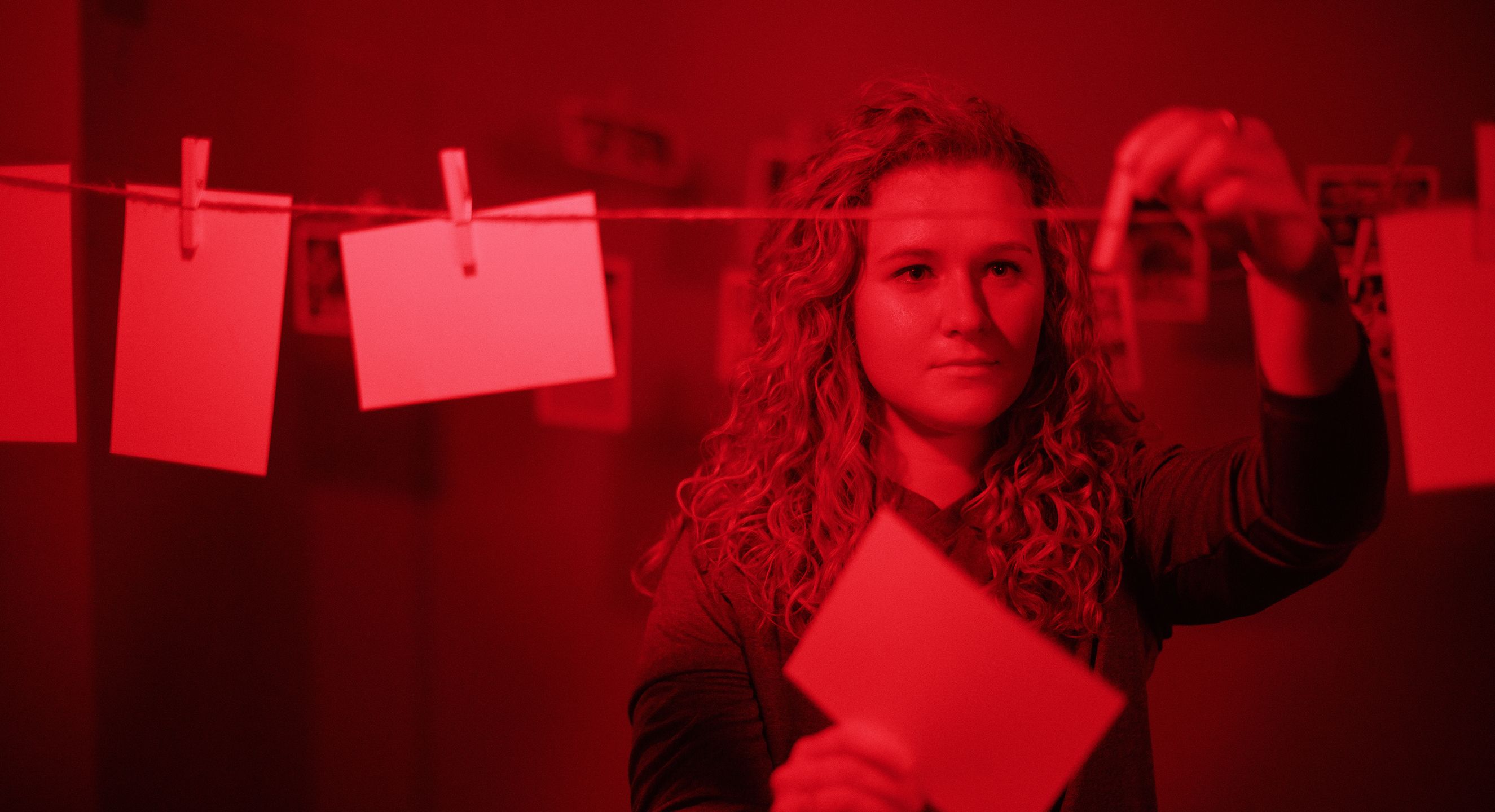 Emily Henderson pins a photo to a line in a darkroom.