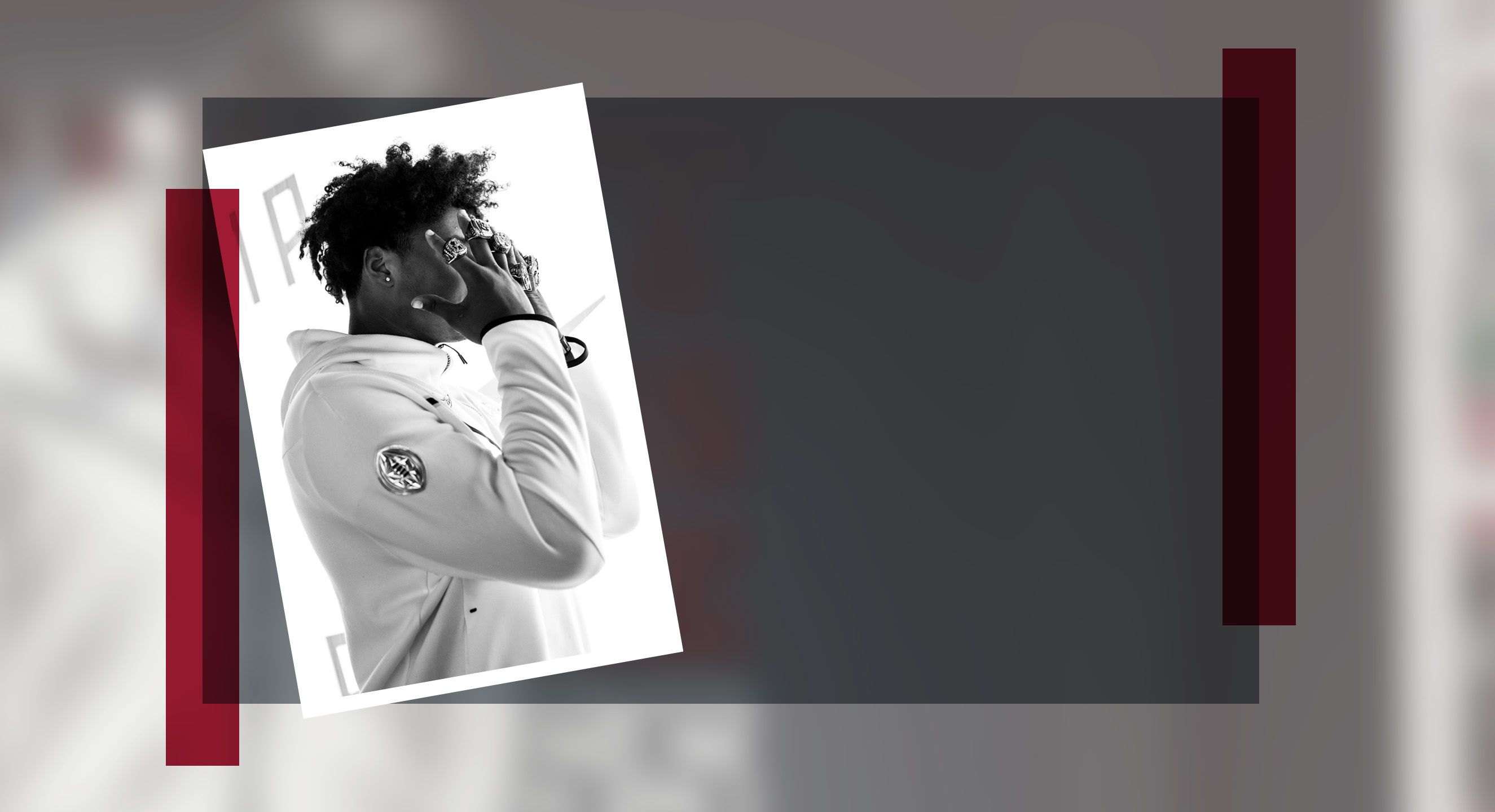 Photo of a football player covering his face with his hands, several rings on his fingers.