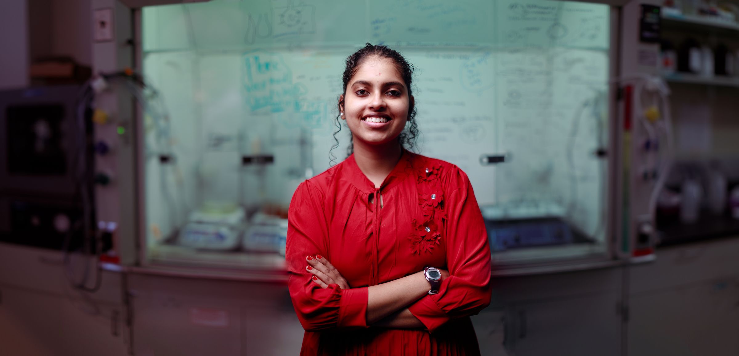 Graduate Student Sandhiya Thiagarajan standing confidently with arms crossed in lab