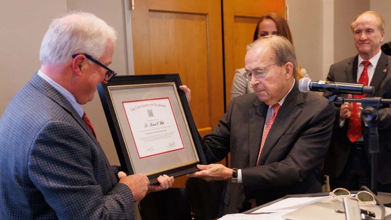 A photo of Dr. Allen Yielding presenting Dr. Robert E. Witt this a plaque.