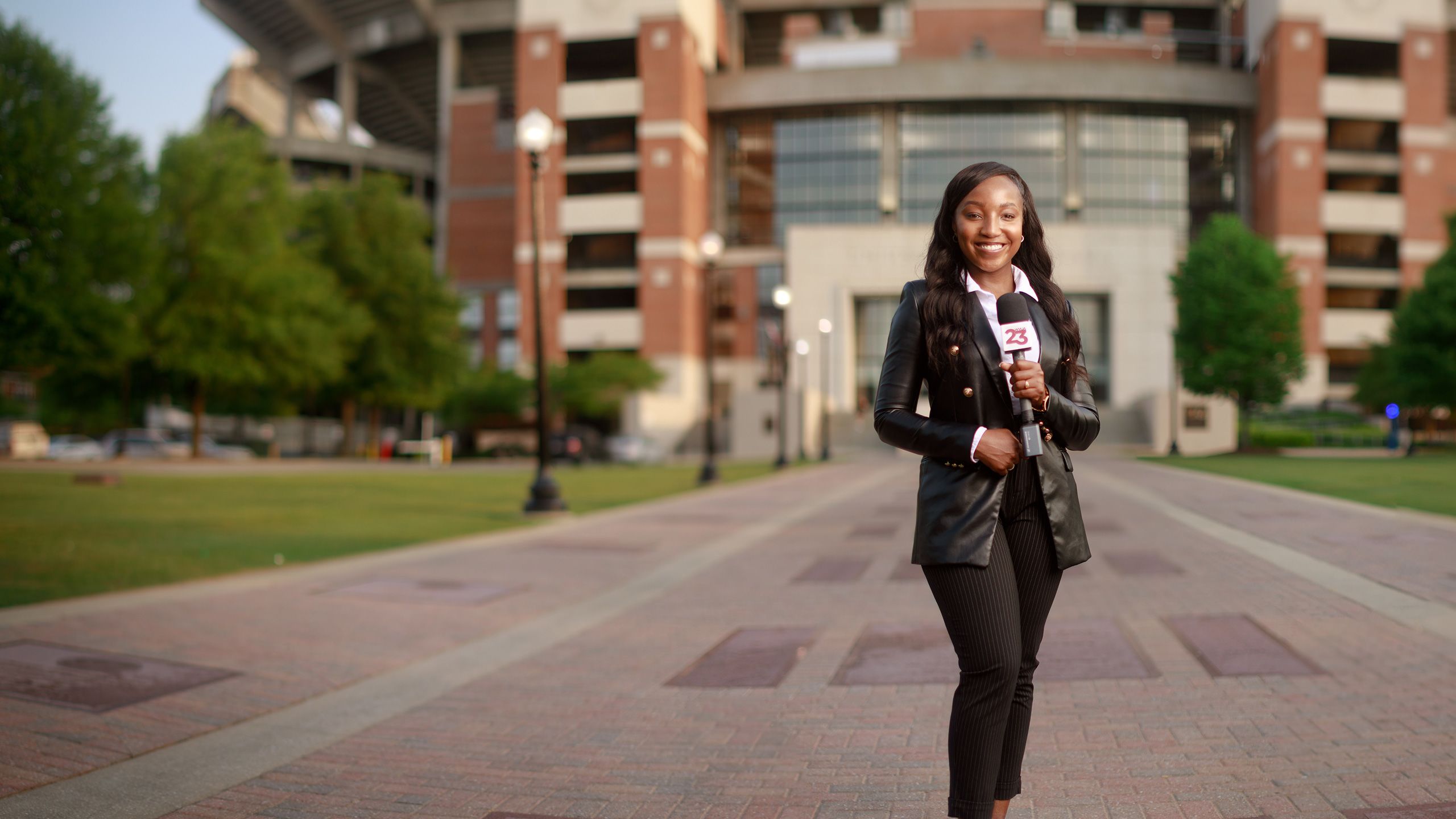 Kennedy stands on the Walk of Champions holding a microphone preparing to go live on camera.