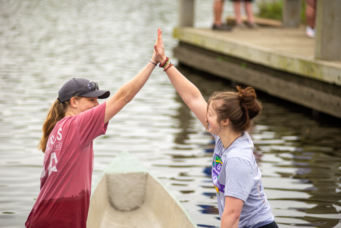 Women's team high-fiving after a strong rowing competition finish at the 2023 regional competition. 