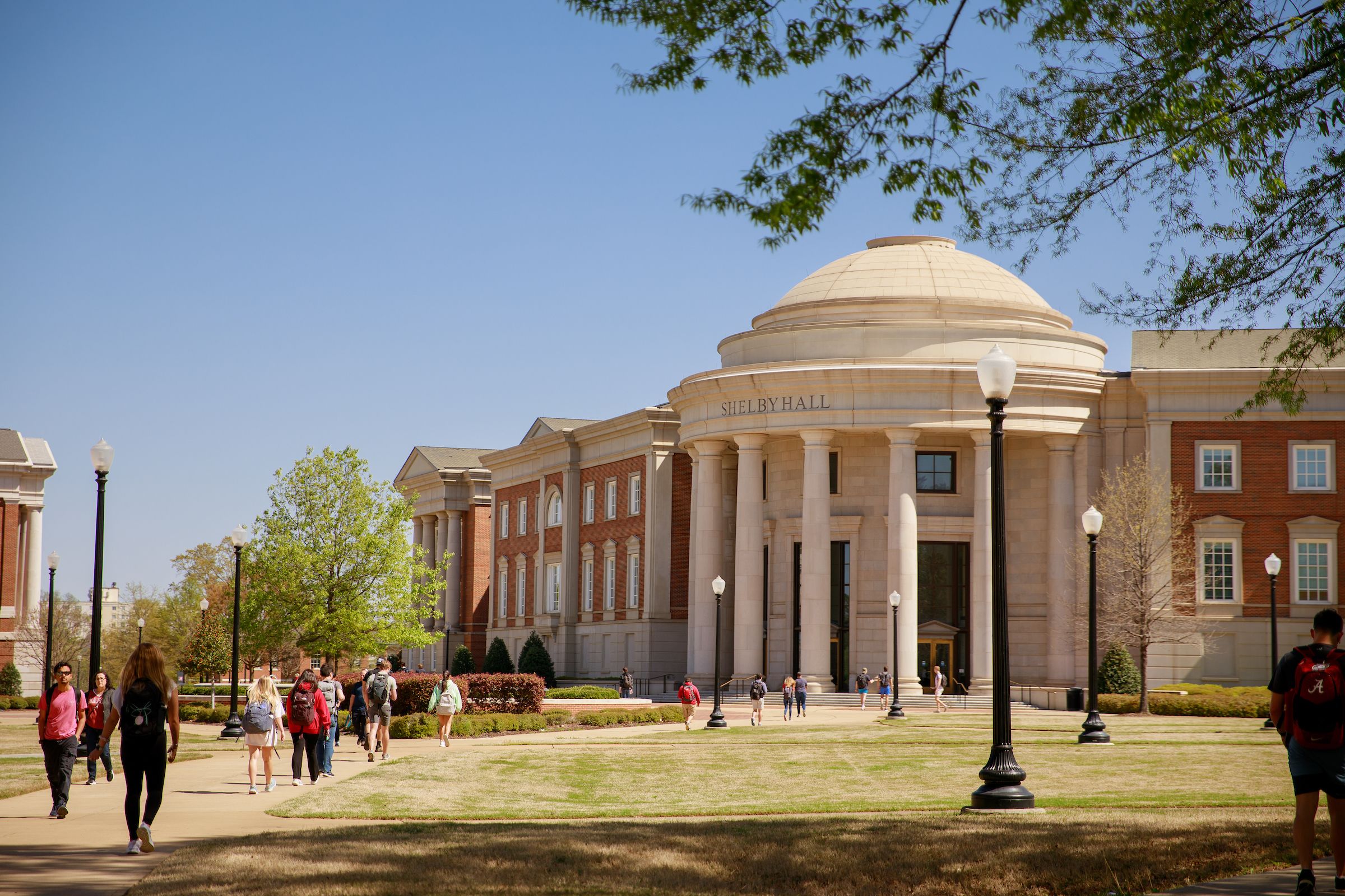 The grand, rounded entrance of Shelby Hall with students arriving on a sunny spring day.