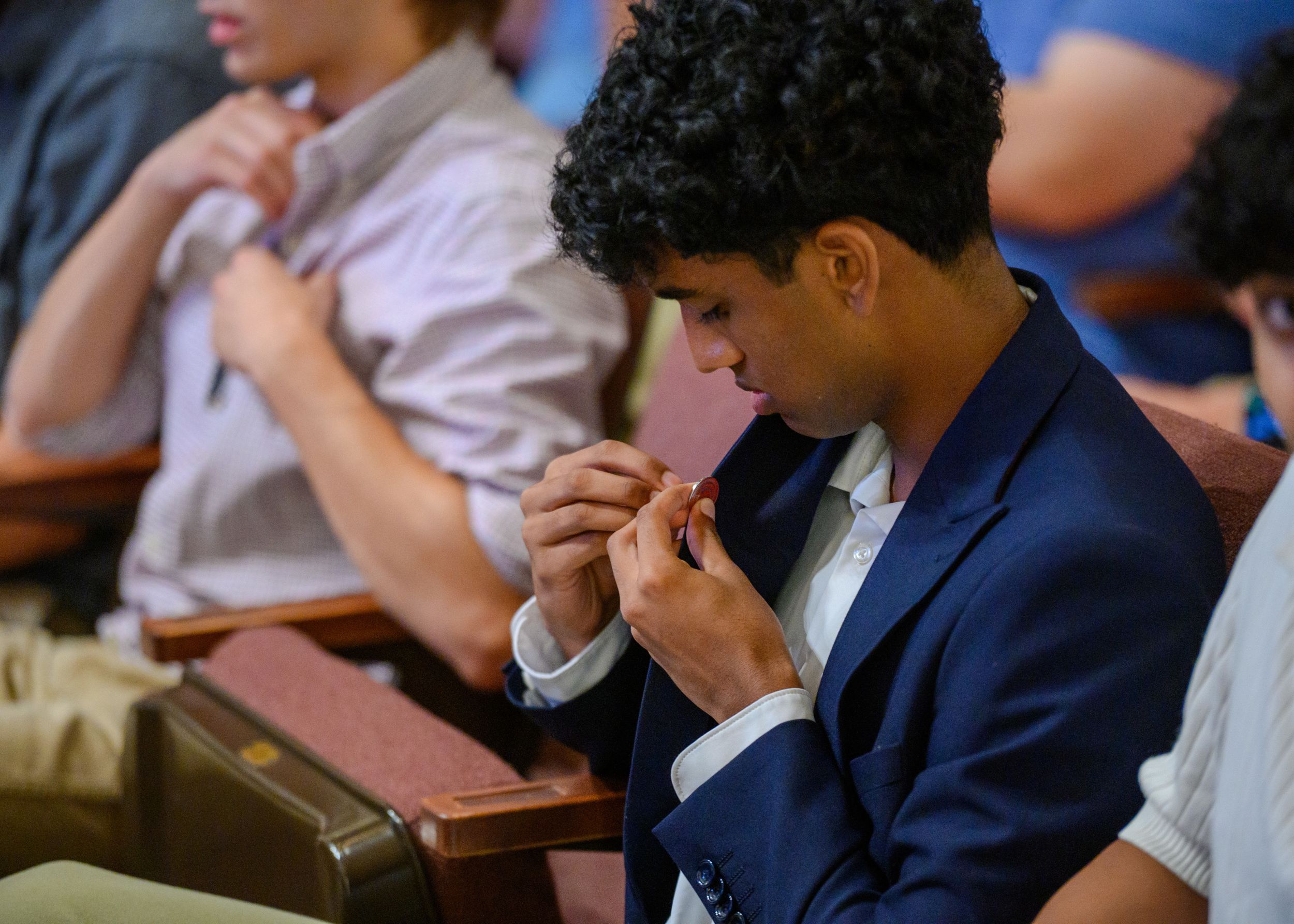 An Honors student puts on the Honors pin at convocation.