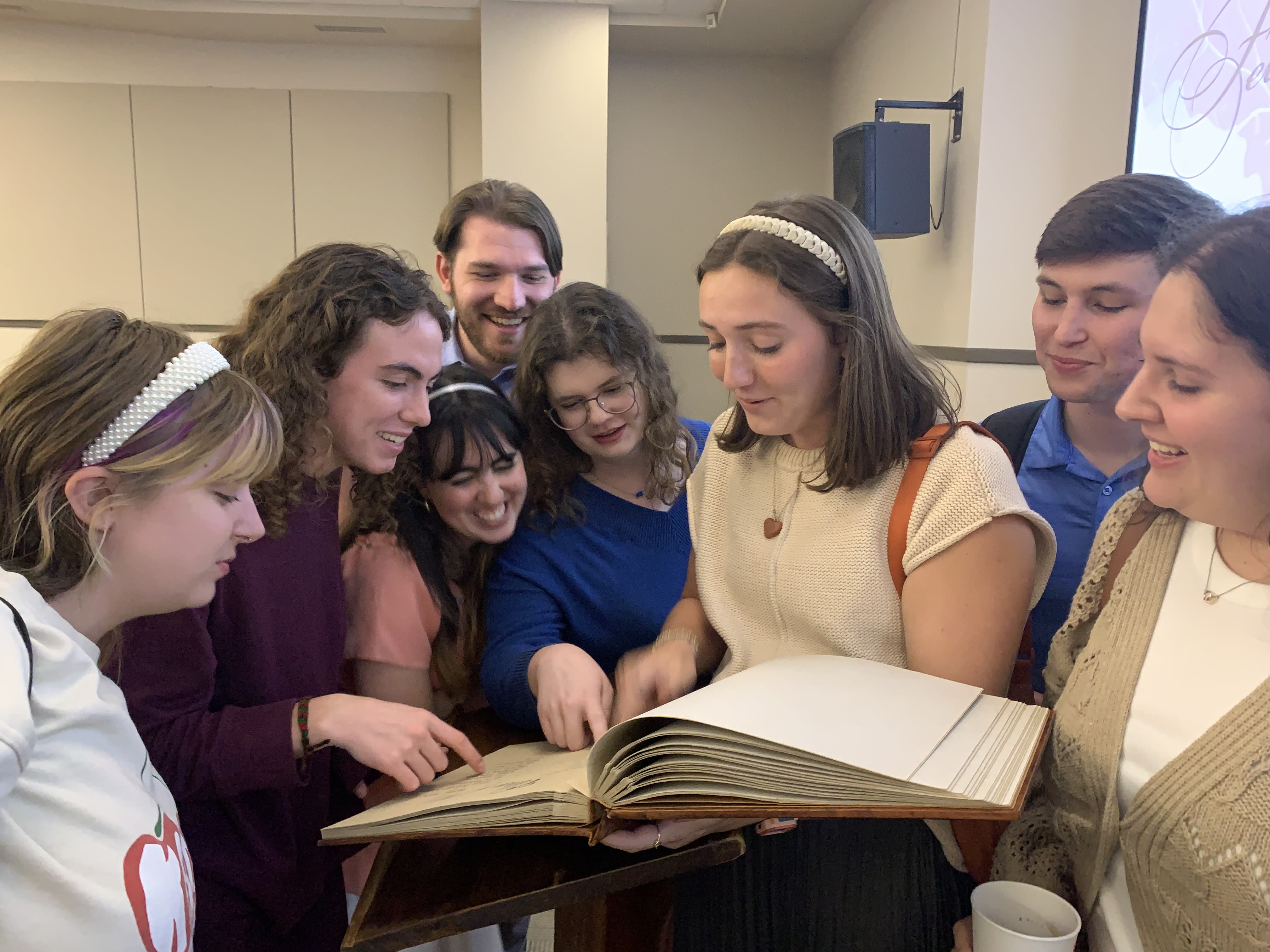 A photo of Witt Fellows gathering around a large book at their signing ceremony.