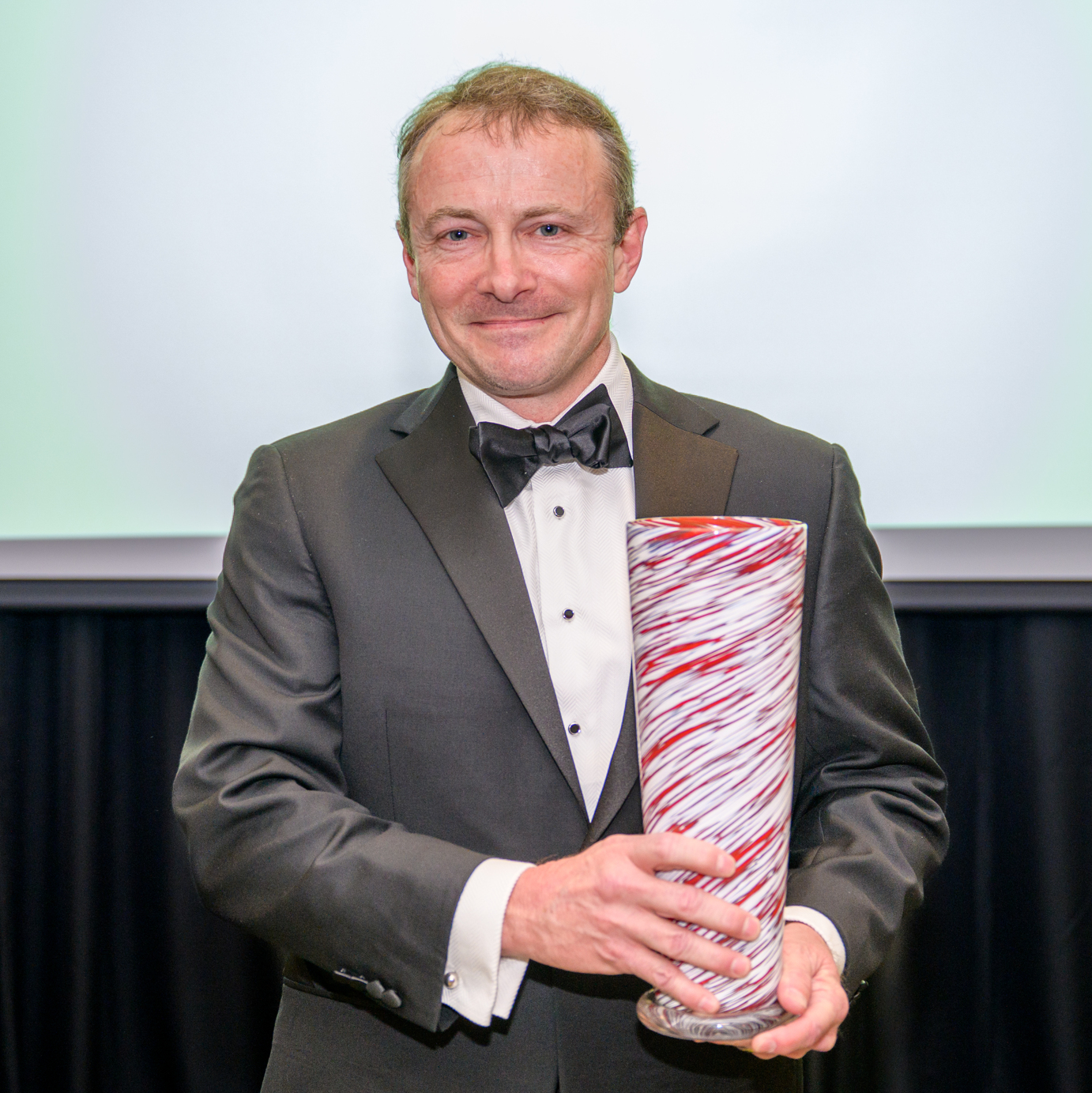 A photo of John Baschab holding his award.