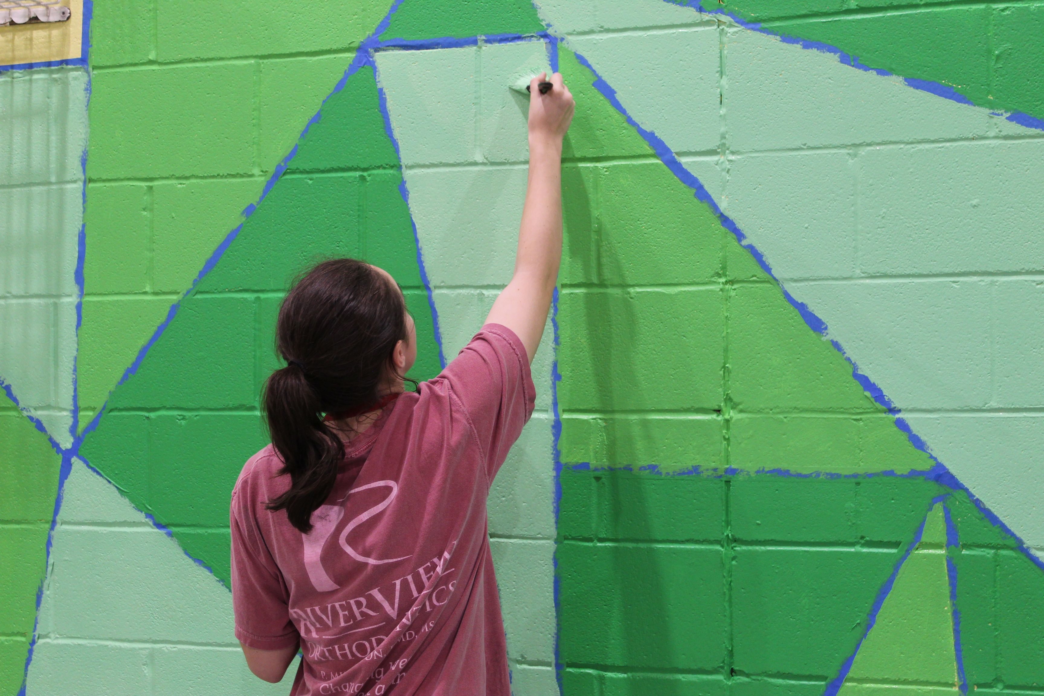 An Honors student paints a mural for Honors Action.