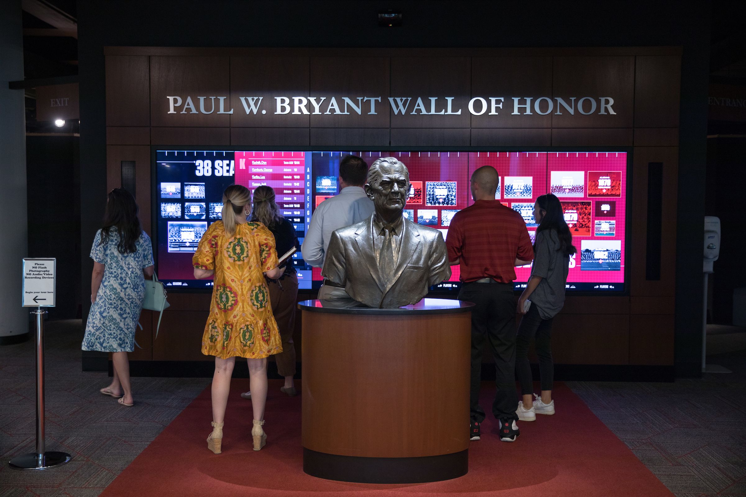 Visitors in front of the Wall of Honor just behind the bust of Paul W. Bryant