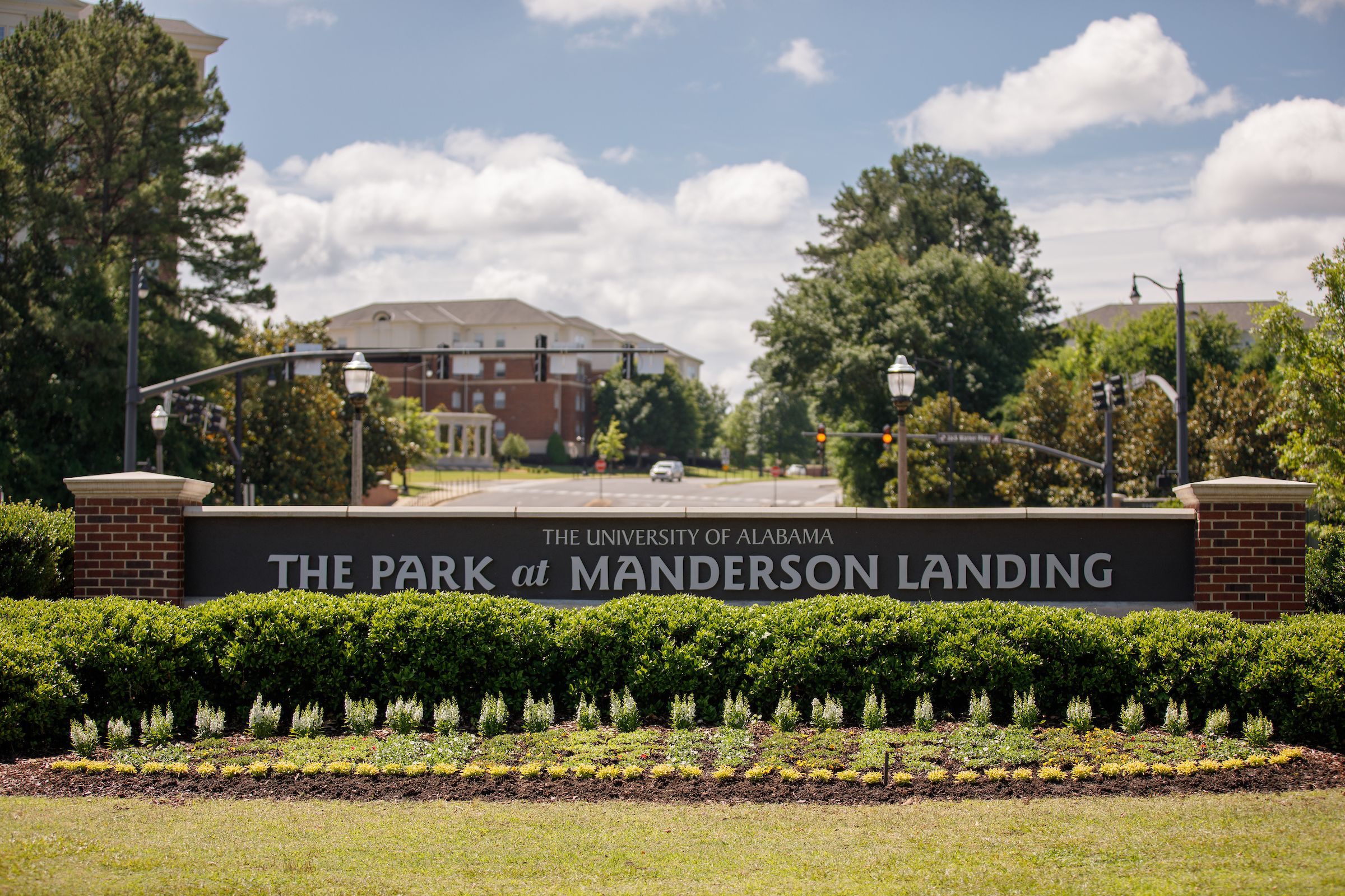 Entryway sign announcing the Park at Manderson Landing, surrounded by bushes and flowers.